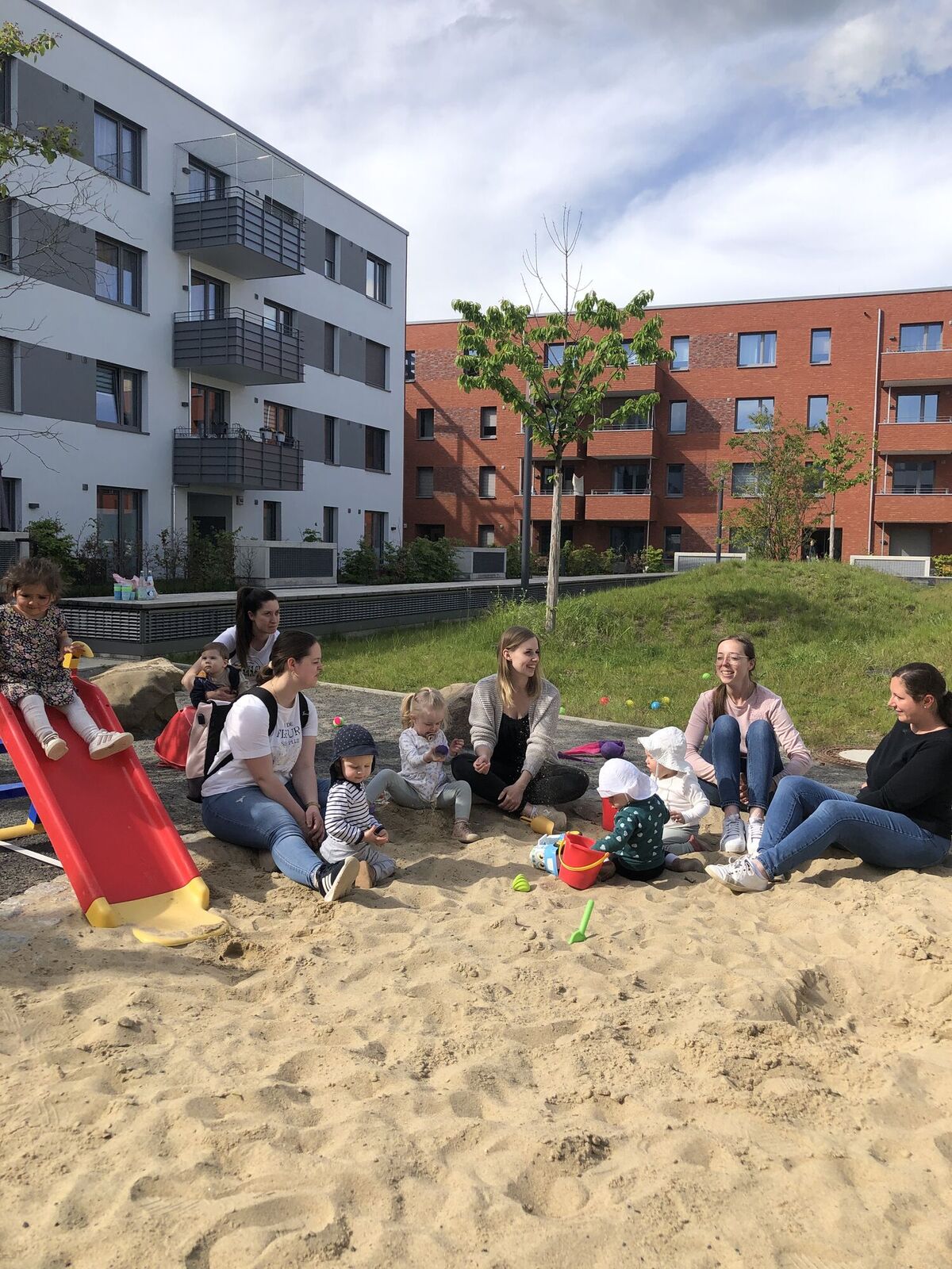 Eltern und Kinder am Sandkasten im Innenhof